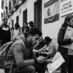 Close-up showing a young man of North African descent anxiously holding his criminal record folder, outside a crowded Spanish "Oficina de Extranjería," with the 'صوت إسبانيا' (Sawt España) logo visible.