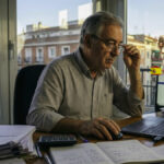 Un hombre autónomo revisando facturas y su declaración de la renta 2025-2026 frente a su ordenador en España.