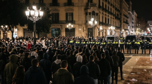 صورة توضيحية لحشد من الأشخاص وعناصر الشرطة خلال تجمع ليلي في ساحة كاتالونيا ببرشلونة.